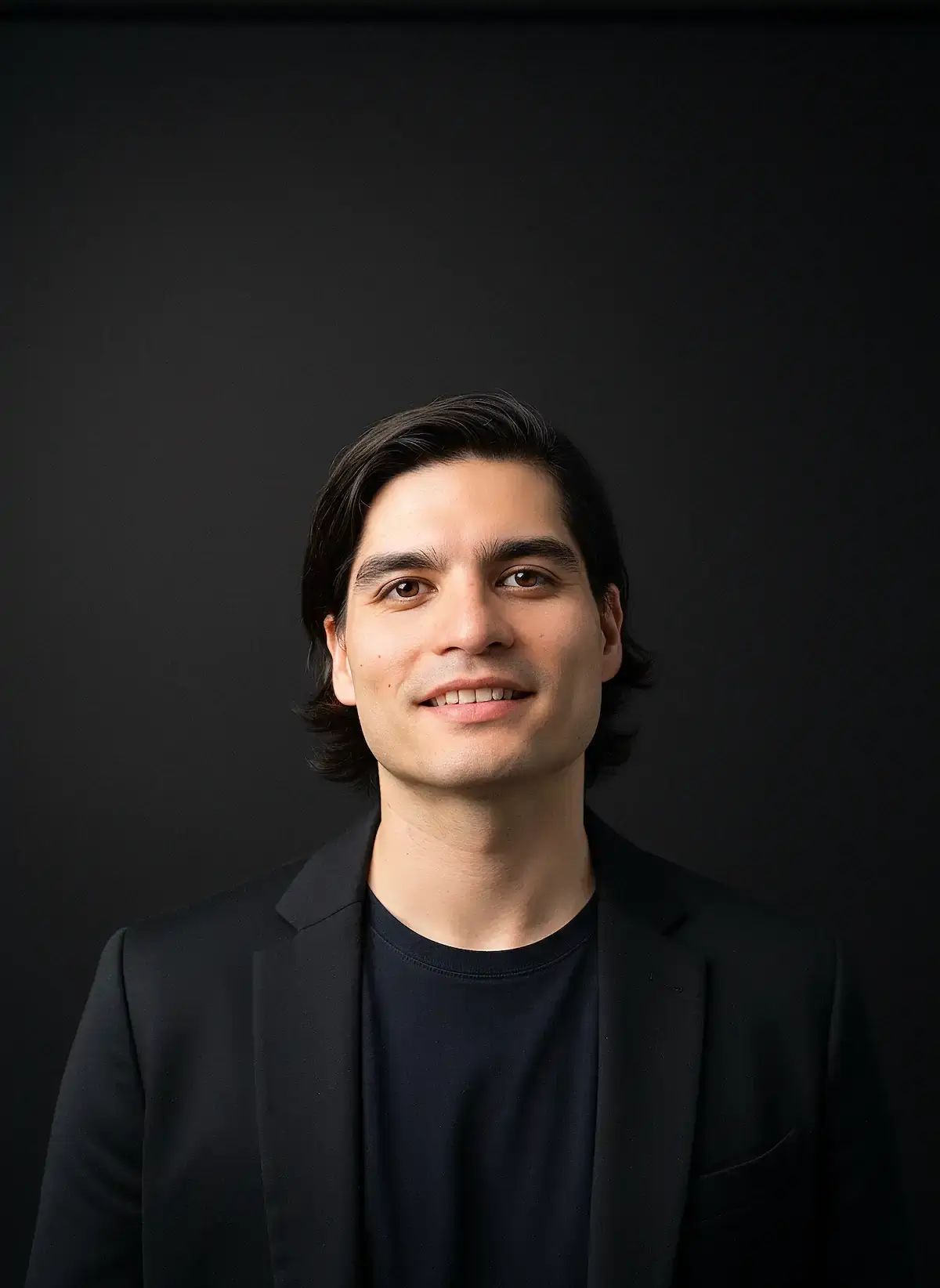 Matt Lok, marketing consultant, smiling in a black blazer against a dark background